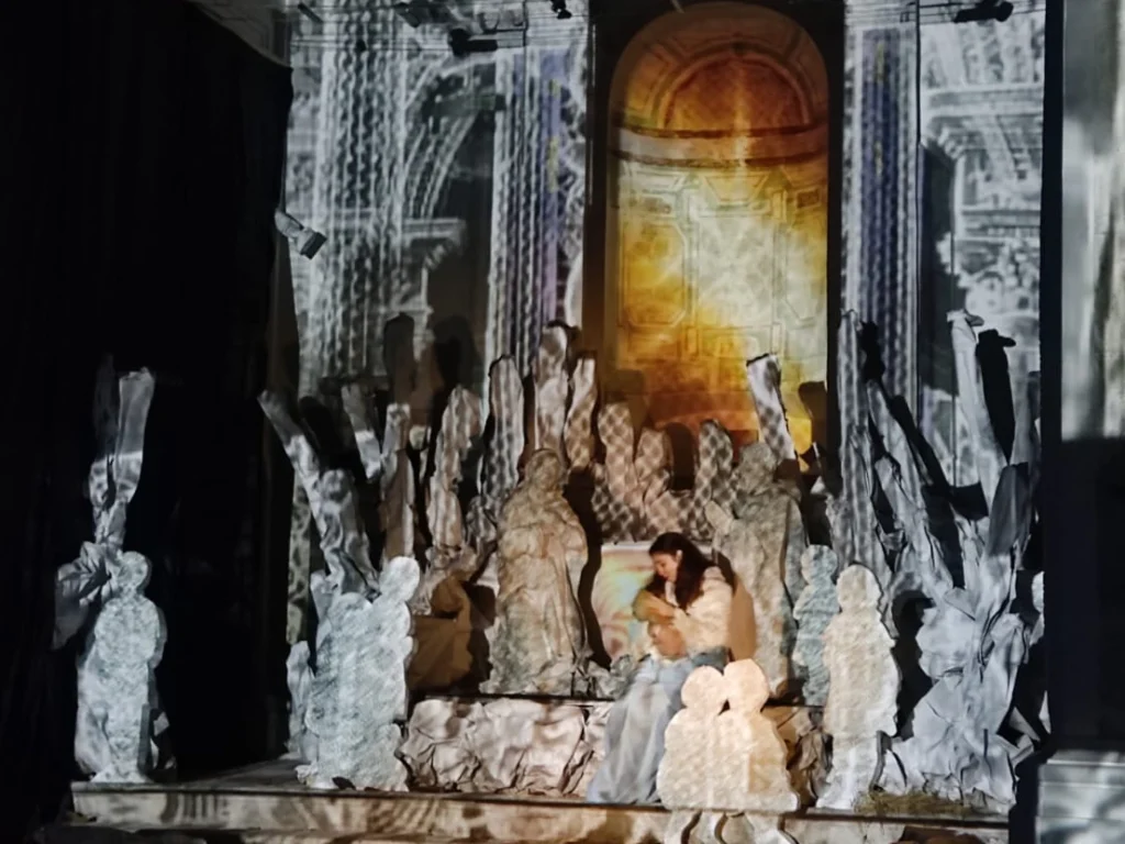 Madonna con il Bambino in braccio tra figure bianche scolpite, illuminate dal video mapping del Presepe d’InCanto a Petralia Soprana